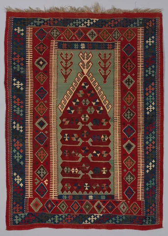 Anatolian kilim with a pointed red central motif on muted green, angular cream outlines, and red and navy geometric borders.