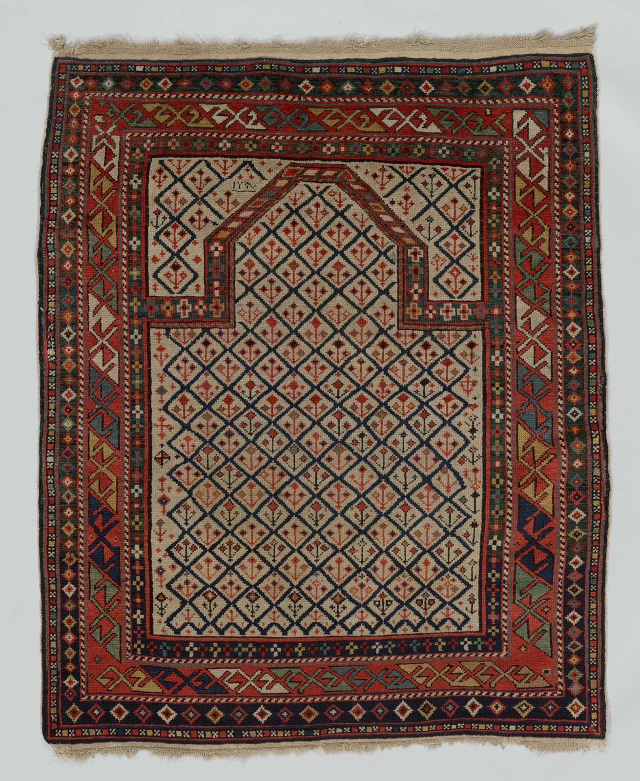 Daghestan prayer rug with a cream diamond lattice beneath a stepped arch and red and navy geometric borders