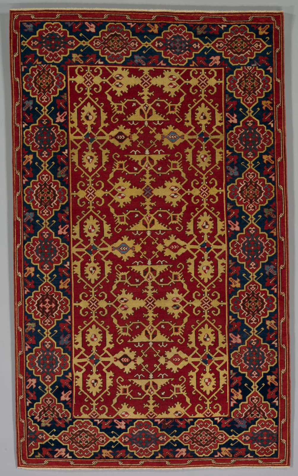 Red Ottoman carpet with a yellow lattice of stylized leaves and a dark blue border