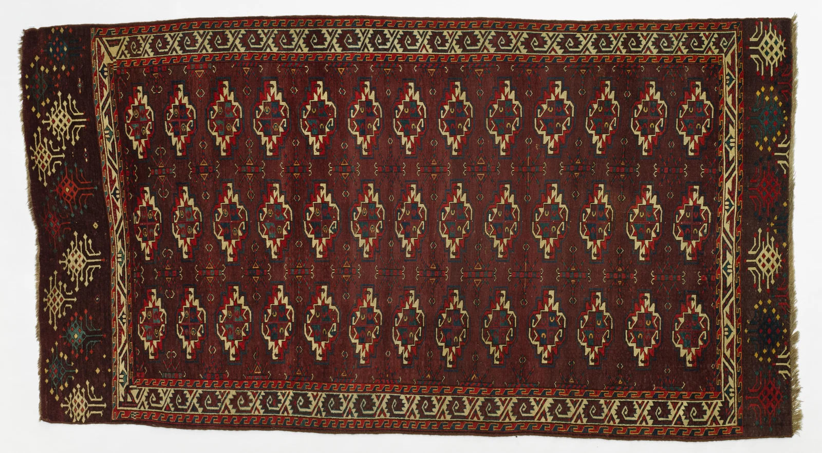 Aubergine-red Turkmen main carpet with repeated guls, geometric borders and decorated end panels